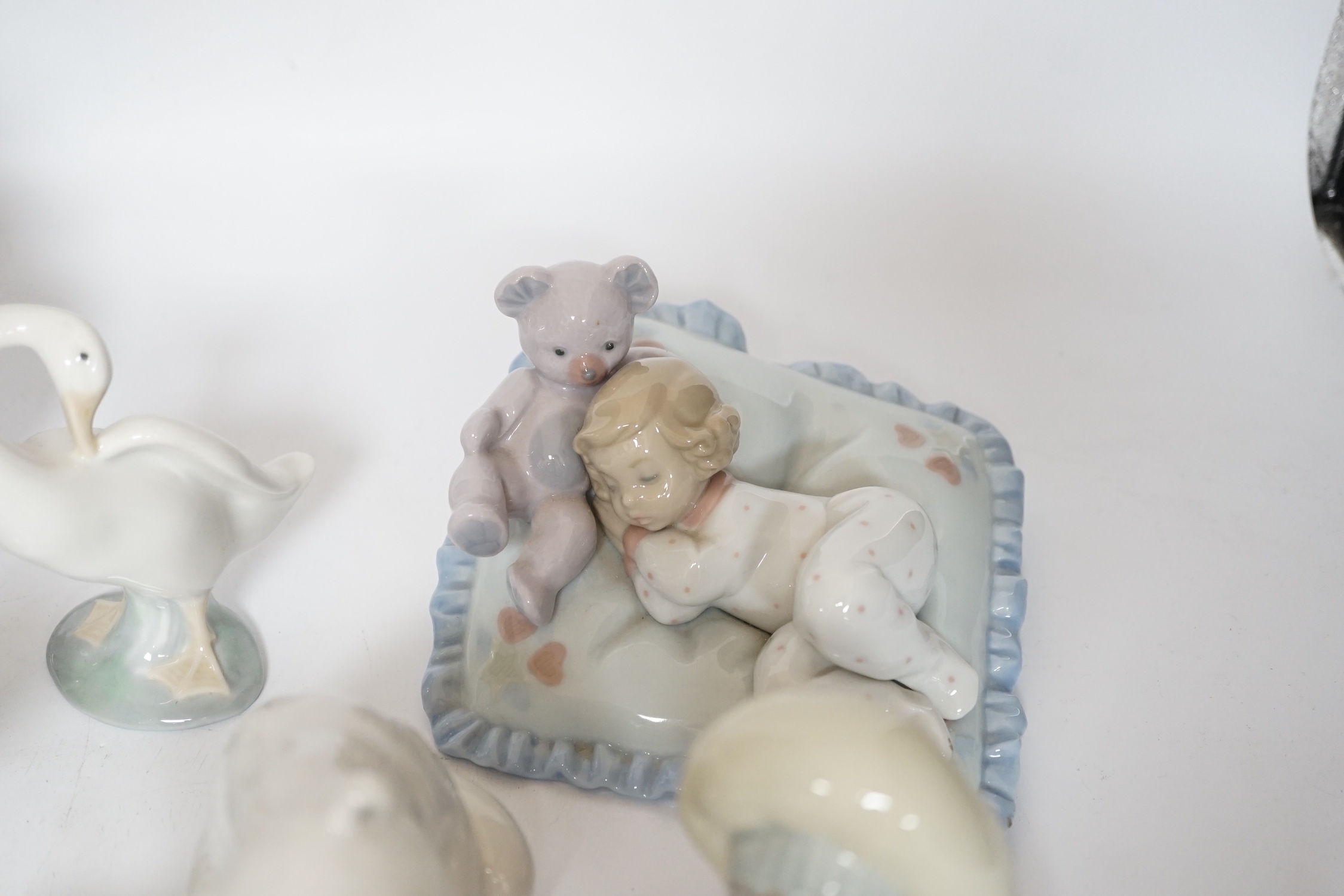 Eleven Lladro figure groups, including a collection of ducks, two Eskimo figure groups, a sleeping child with teddy on a cushion etc, none boxed